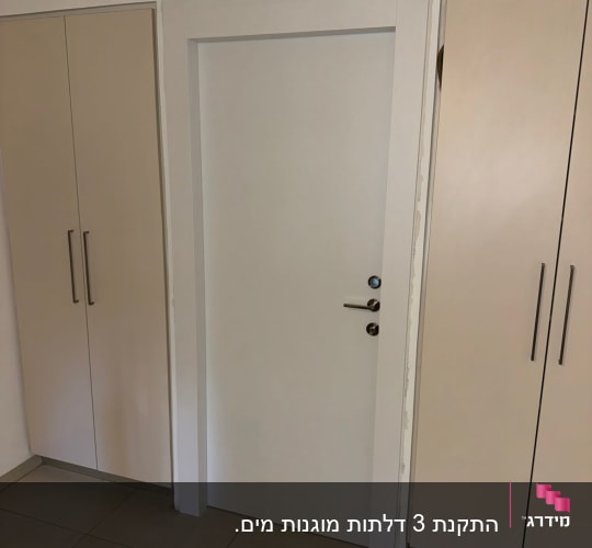 דלת לבנה בין ארונות עם ידיות מתכת